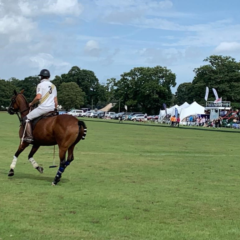 New Forest Polo Club Big Weekend A polo player canters in front of a crowd during a match at NFPC